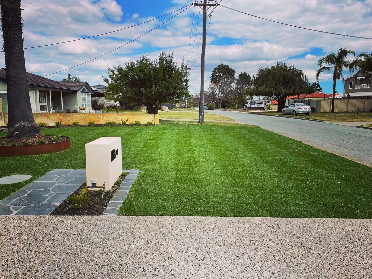 A wide front lawn mown into clean, even stripes right up to the kerb