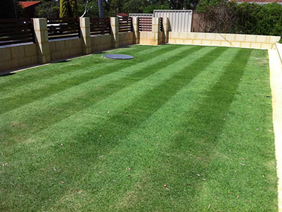 Striped backyard with limestone retaining wall, freshly mowed